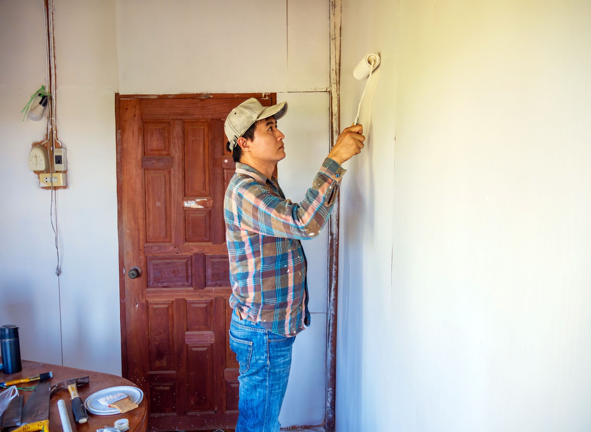 Workers painter are painting the wooden walls of the room white with paint roller,improvement home interior concept.